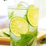 Green text overlay on glass of cucumber mint lime water. White background.