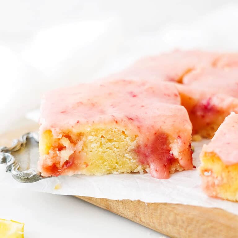 Glazed strawberry lemon blondie on parchment paper and wooden board. White background.