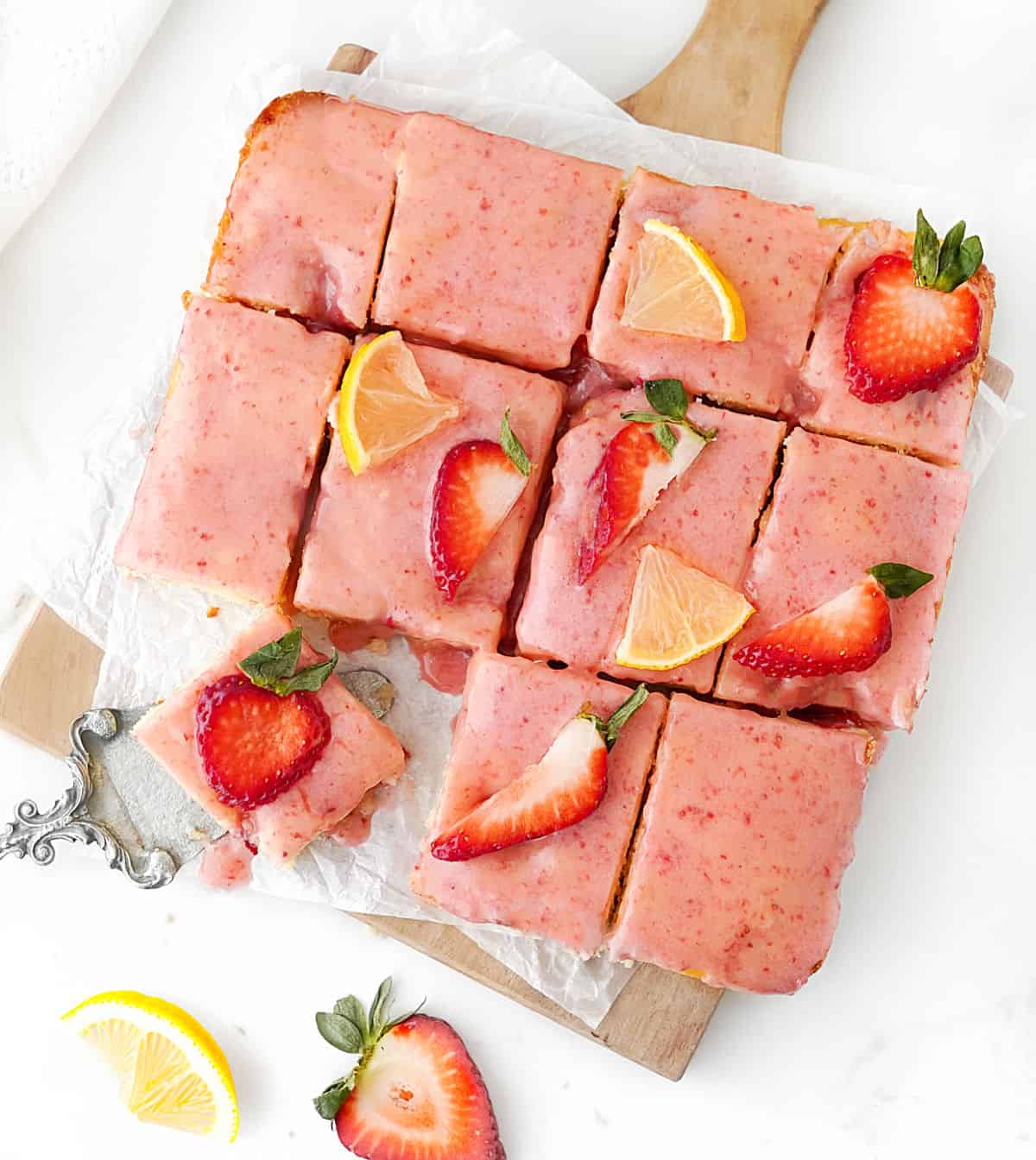 Top view of glazed lemon strawberry blondie squares on a white surface. 