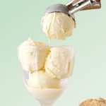 Green background with vanilla ice cream being scooped into a glass.