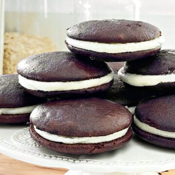 Close up pile of classic whoopie pies with cream cheese filling. White cake stand.