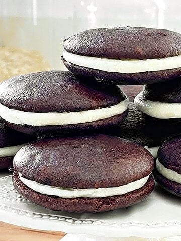 Close up pile of classic whoopie pies with cream cheese filling. White cake stand.