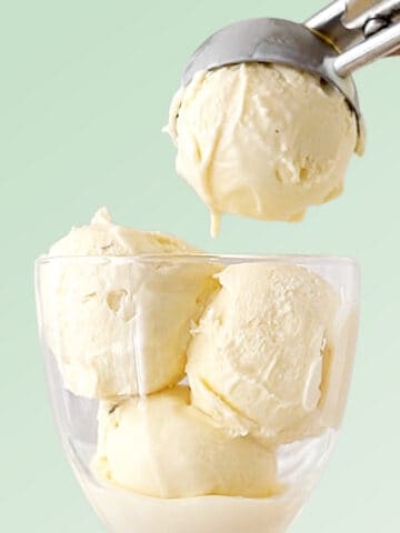 Mint green background with vanilla ice cream being scooped into a glass.