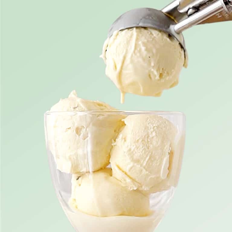 Mint green background with vanilla ice cream being scooped into a glass.