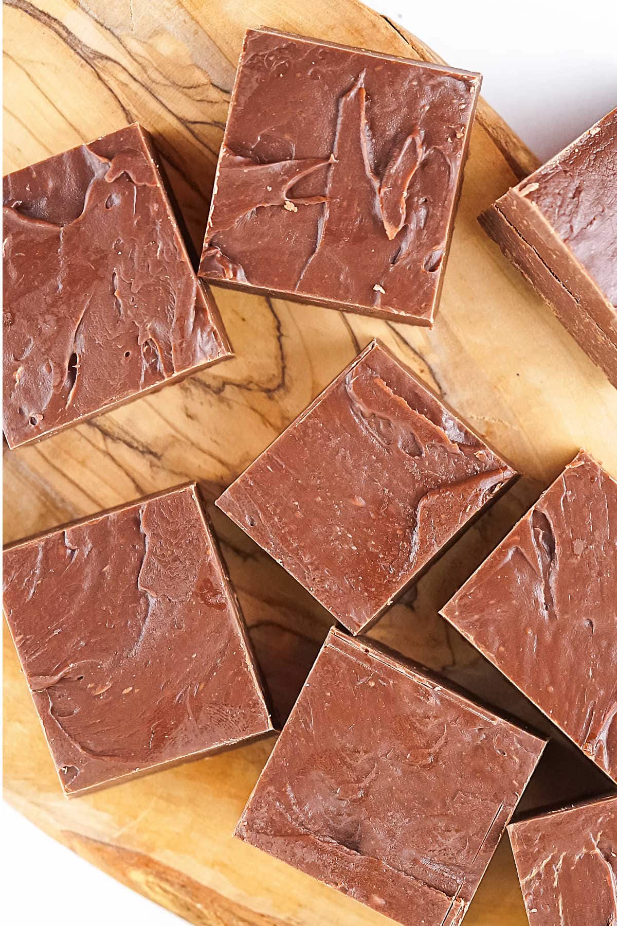 Top view of easy chocolate fudge pieces on a light wooden board. 