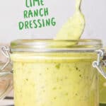 Green text overlay on mason jar with spoon and avocado ranch dressing. Wooden board, grey background.