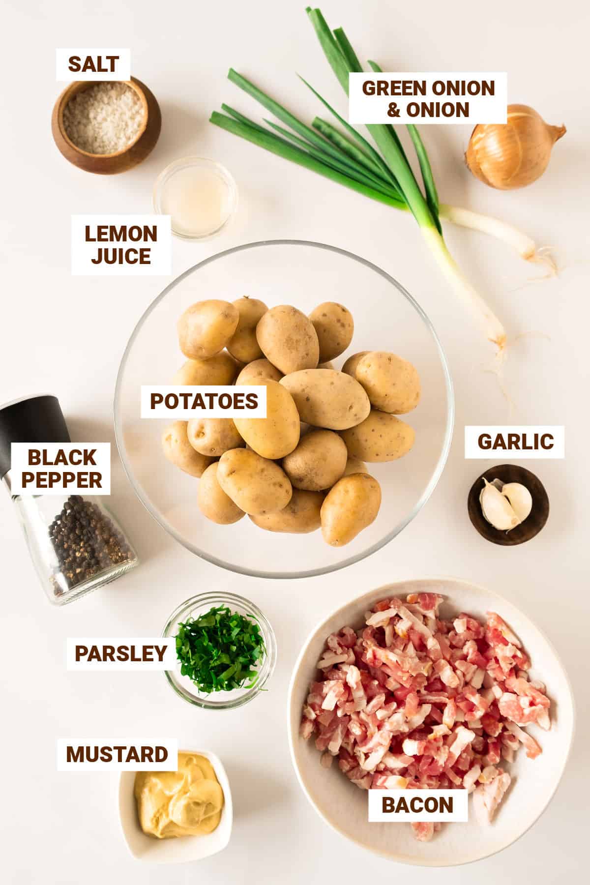 Ingredients for bacon potato salad with onions in bowls. White background.