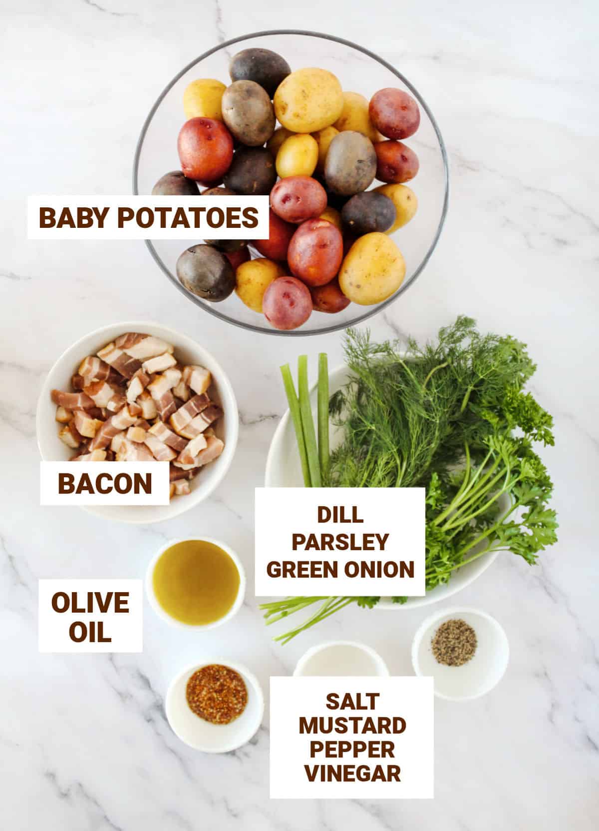 Ingredients for potato salad in bowls on a white marbled surface with text overlay including fresh herbs, bacon, oil, mustard, vinegar.