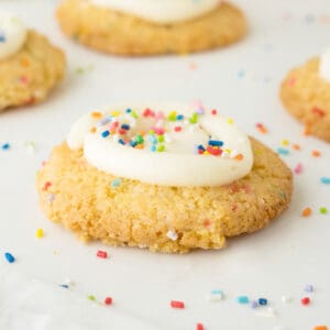 Close up of funfetti cookie with frosting. White surface with sprinkles.