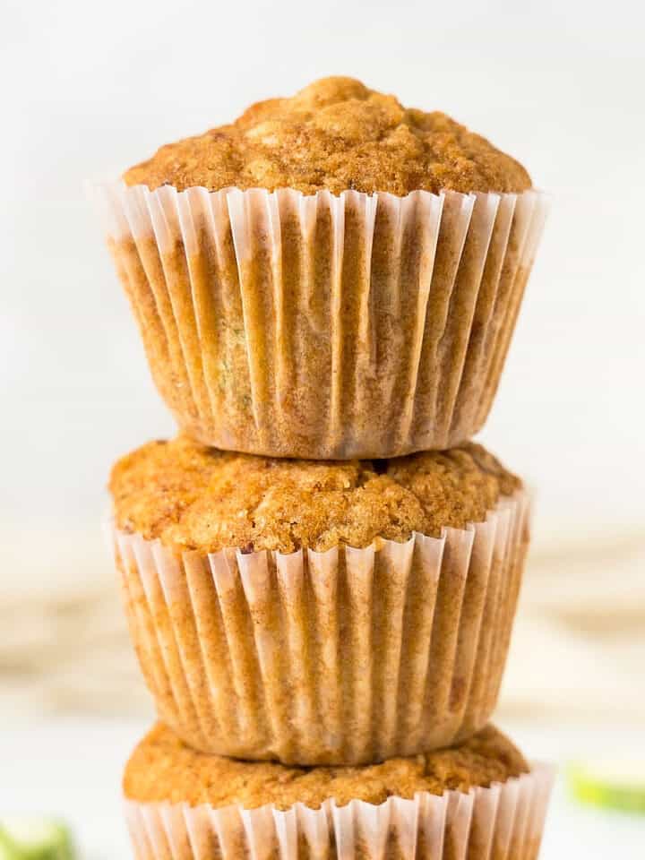 Close up stack of zucchini carrot muffins in paper liner. White background.