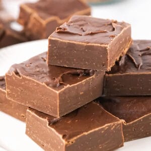 Close up pile of condensed milk fudge squares on a white plate.