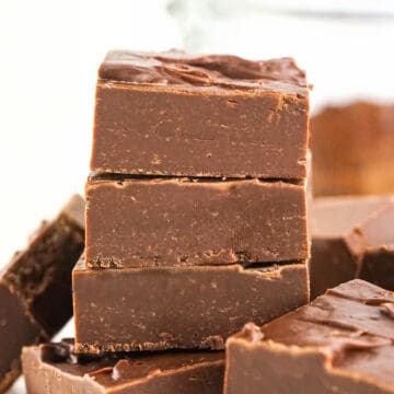 Chocolate fudge squares in a stack with a white background.