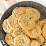 Brown and white text overlay on metal plate with pile of butterscotch chocolate chip cookies.