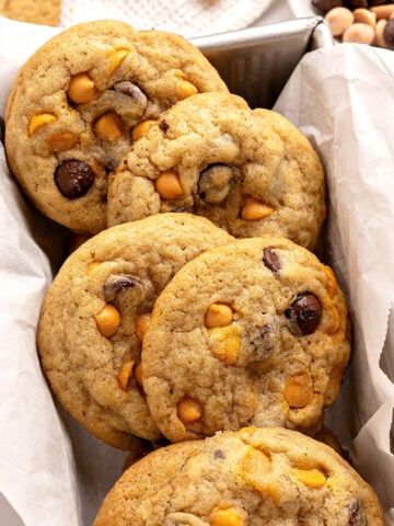 Close up butterscotch chocolate chip cookies on a white parchment lined loaf pan.