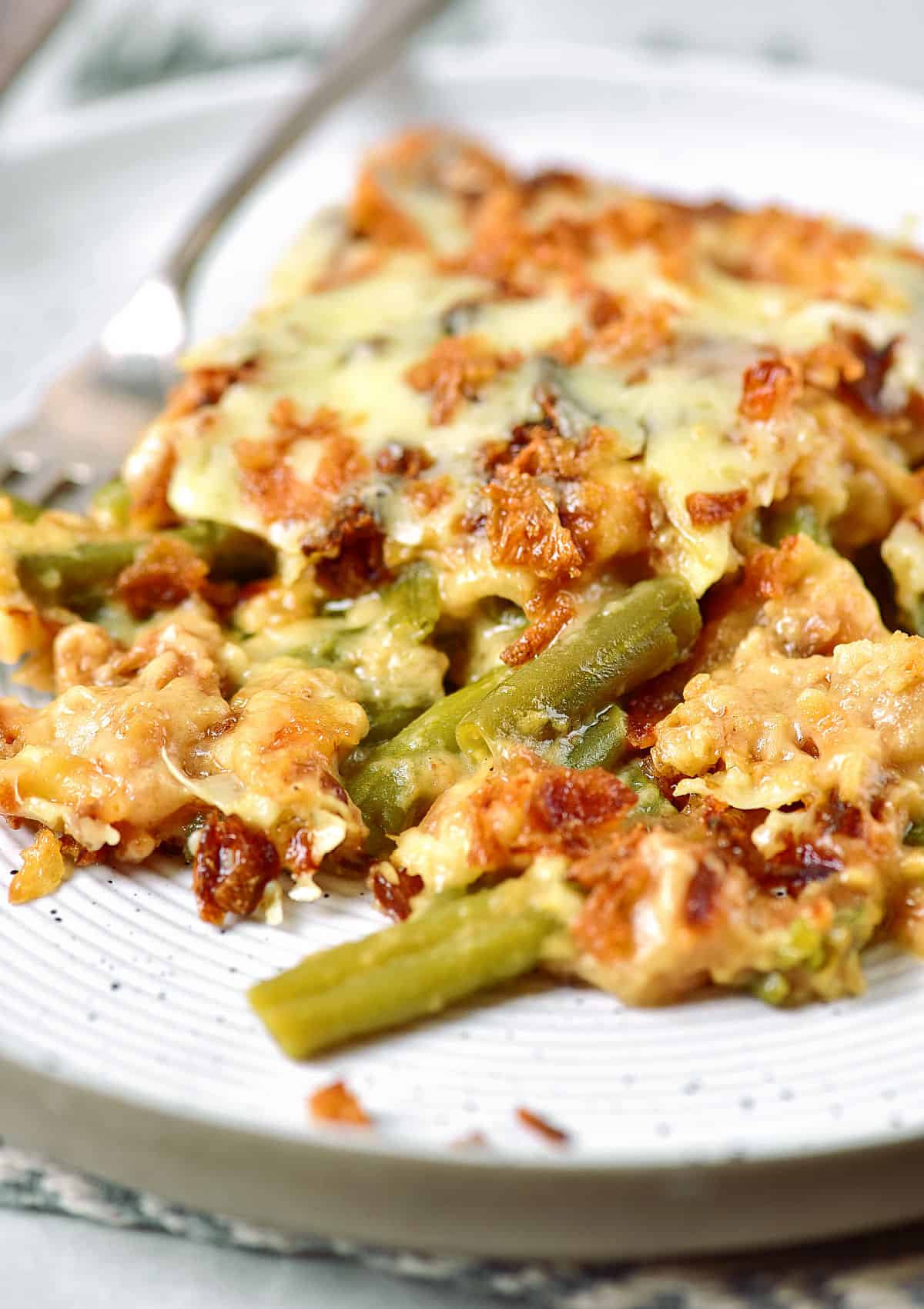 Close up of green bean casserole serving on a light grey plate. 