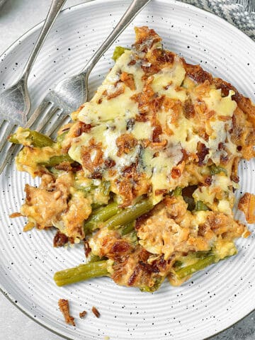 Light grey plate with serving of green bean casserole. Two silver forks.