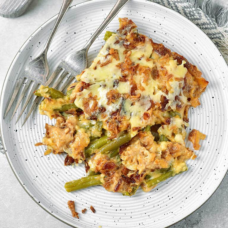 Light grey plate with serving of green bean casserole. Two silver forks.