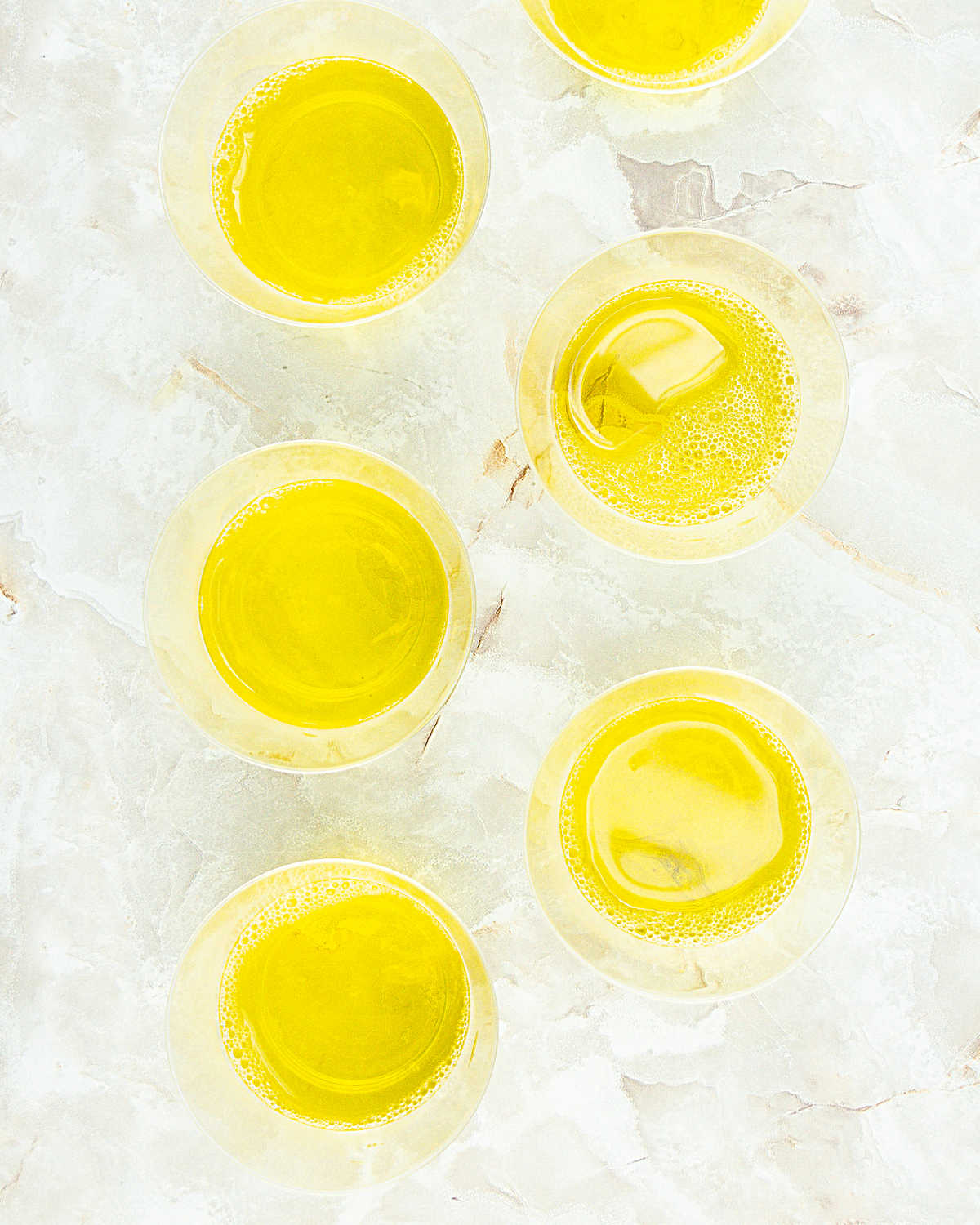 Top view of glass cups with yellow jello. White grey marbled surface. 