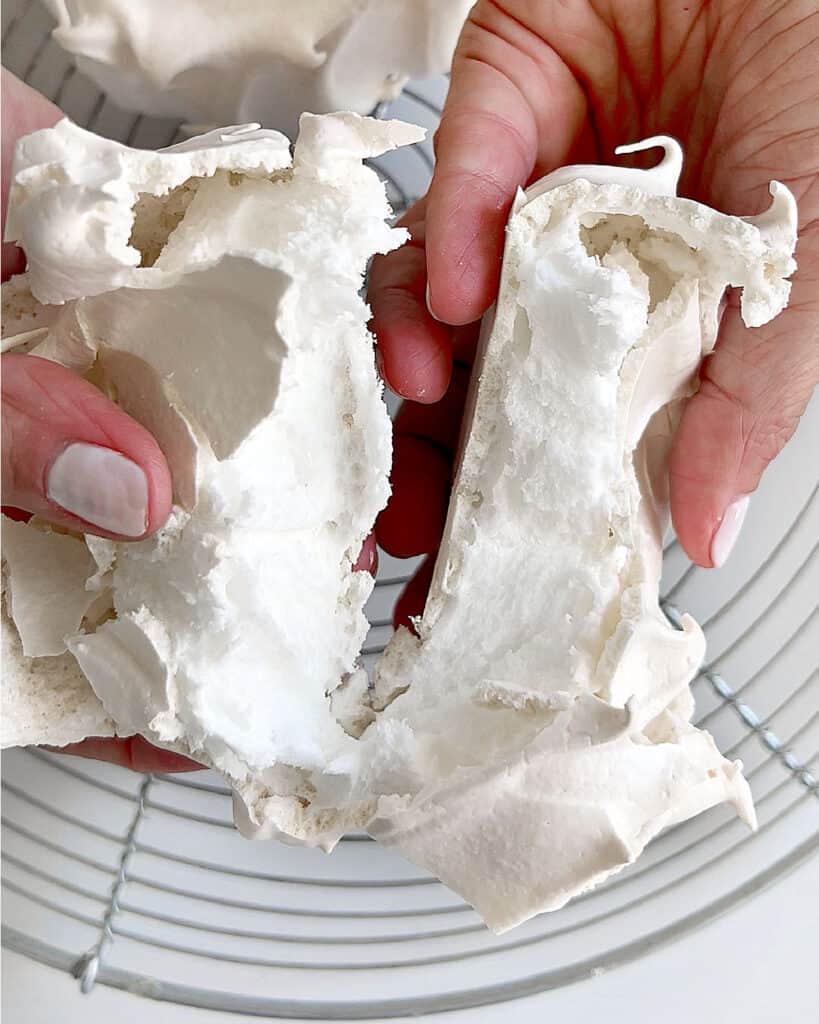 Halved small pavlova disc over a wire rack.