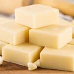 Pile of white chocolate fudge squares on a wooden surface.