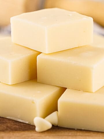 Pile of white chocolate fudge squares on a wooden surface.