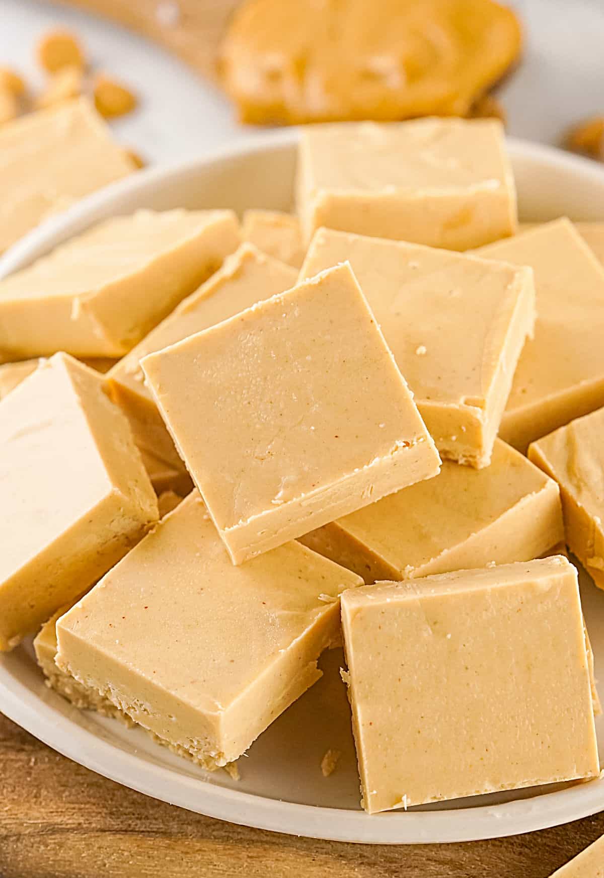 Several squares of peanut butter fudge on a whitish plate. Wooden surface. 