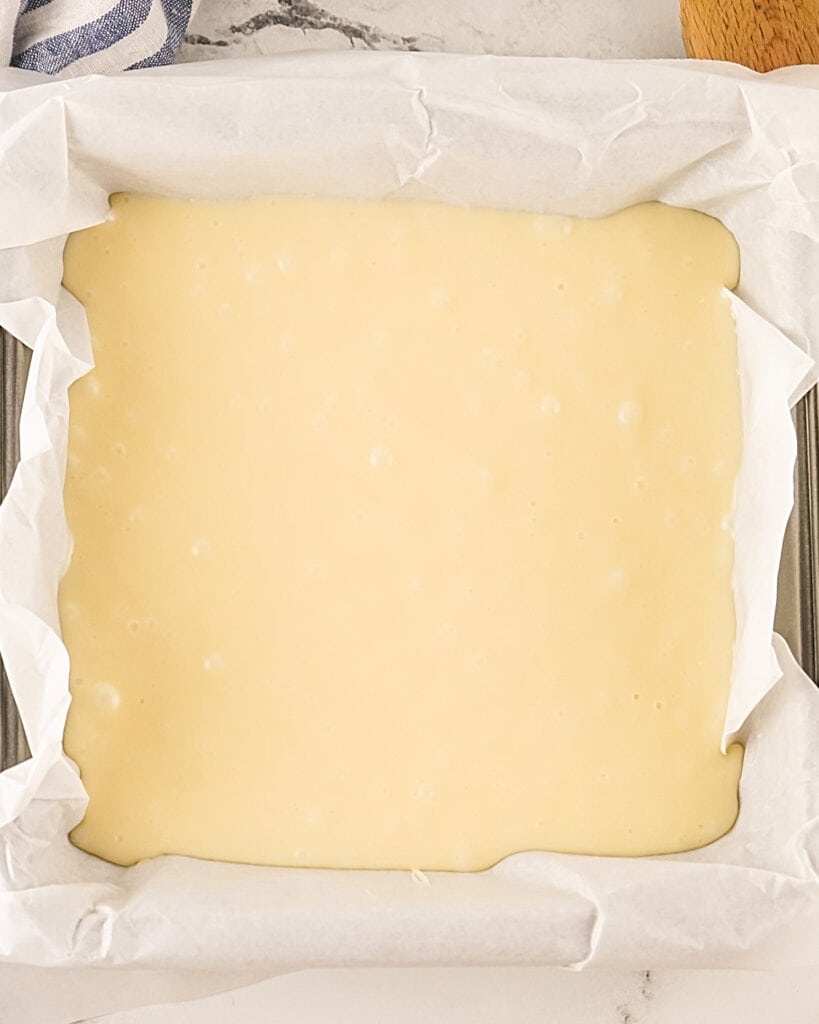 White chocolate fudge in a parchment lined square pan.