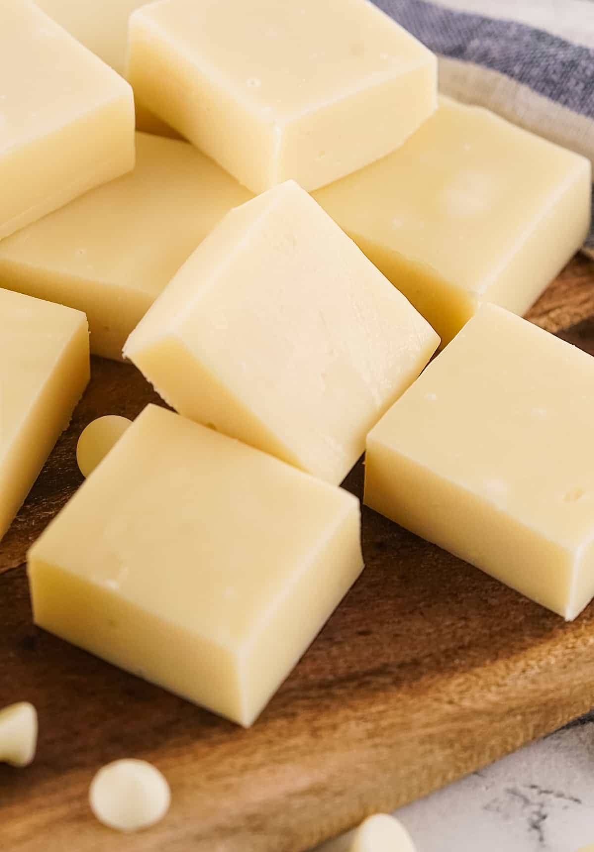 Several squares of vanilla fudge on a wooden board.