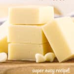 Brown text overlay on image of stack of white chocolate fudge squares on a wooden board.