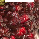 Red, white and black text overlay on close up image of cranberry sauce in a white bowl.