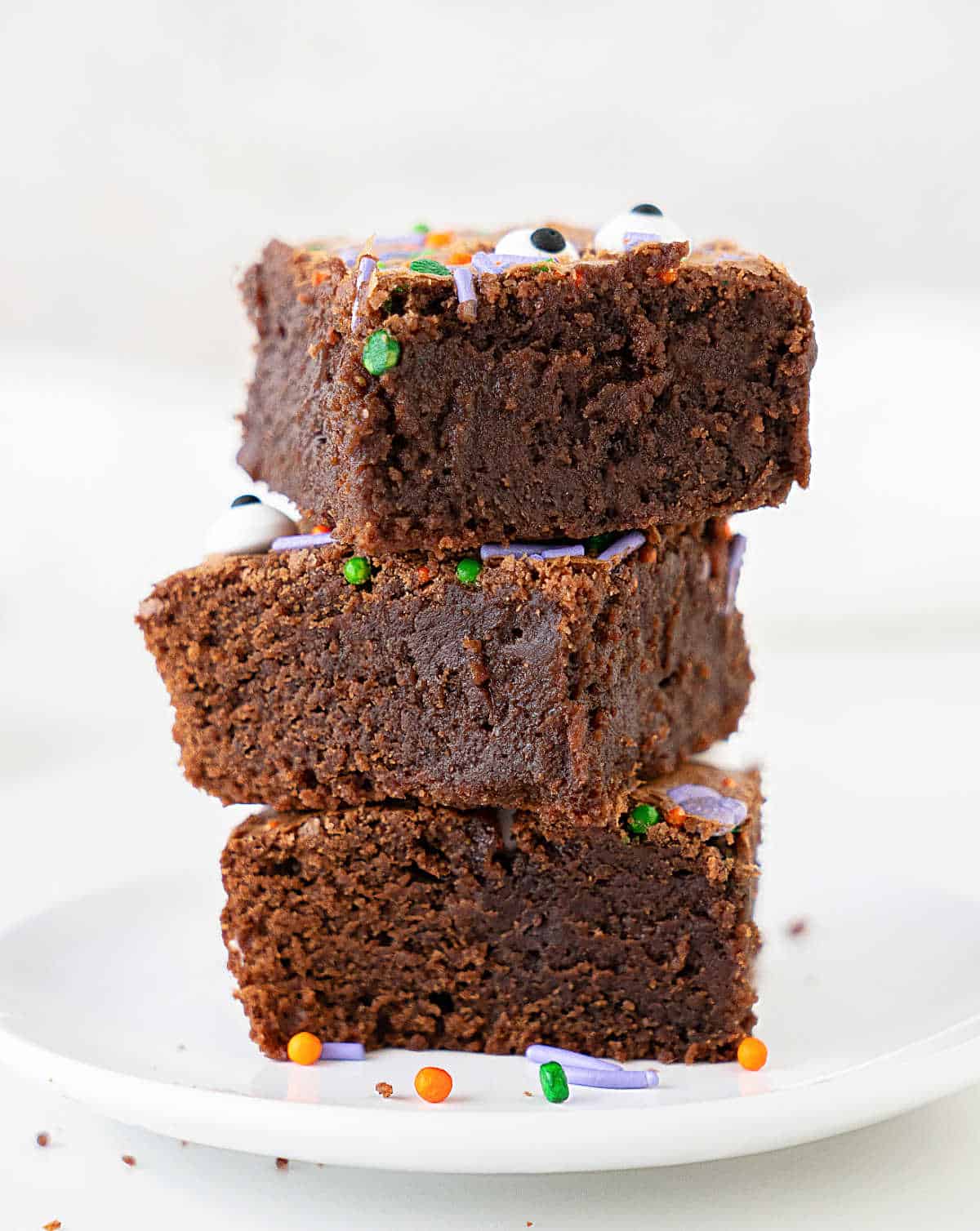 Three halloween brownies stacked on a white plate. White background.