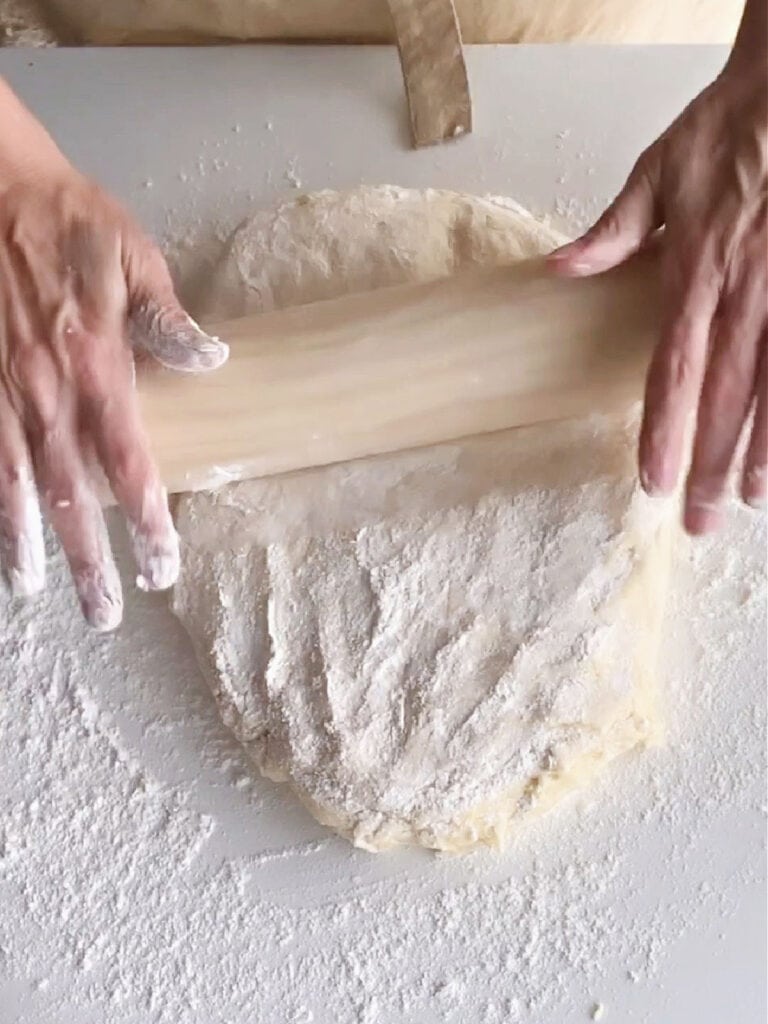 Rolling floured parker rolls on a white surface.