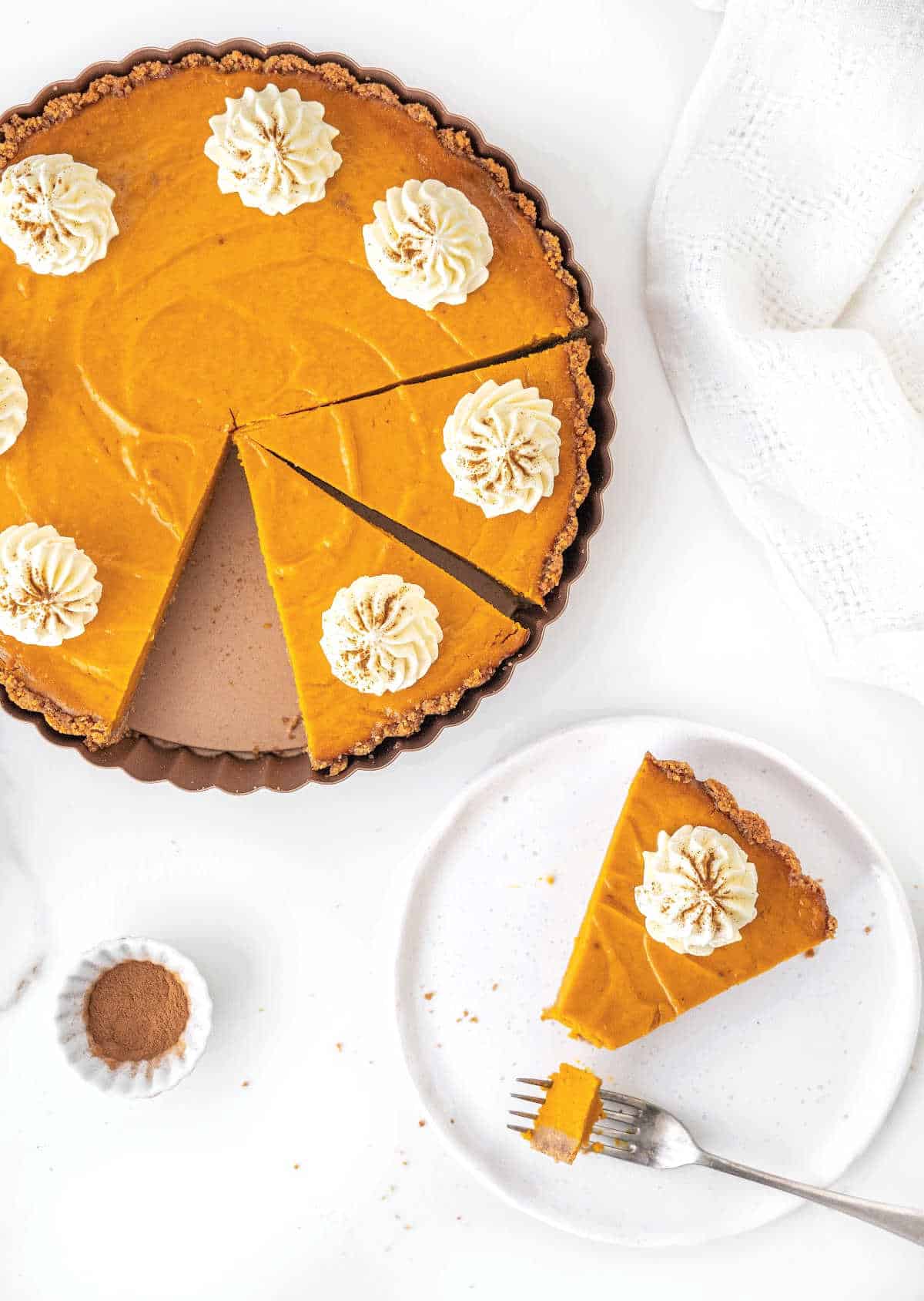 Top view of sweet potato pie in the pan, slice on a white plate. White background.