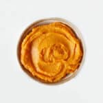 Top view of bowl with sweet potato puree on a white surface.