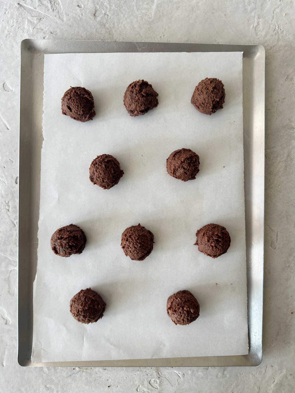 Metal baking sheet with chocolate cookie dough balls. Top view.