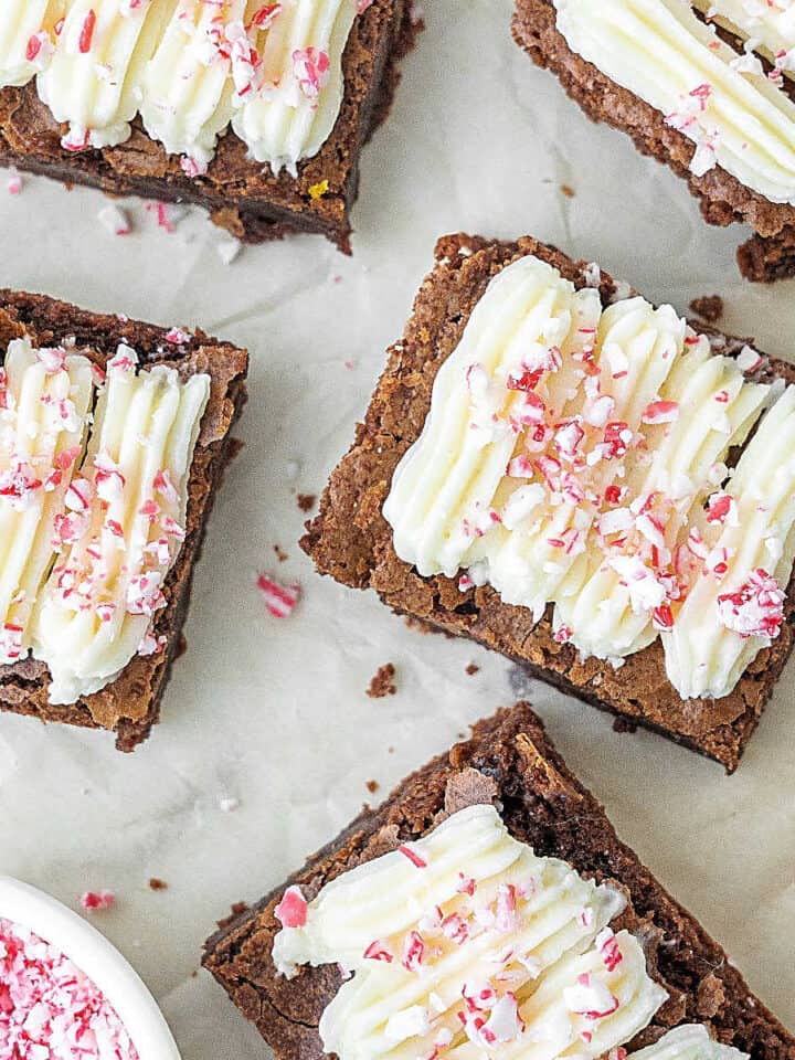 Close up brownies with cream cheese peppermint topping on white marble.
