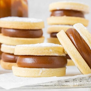 Close up of several shortbread dulce de leche alfajores on a white paper.