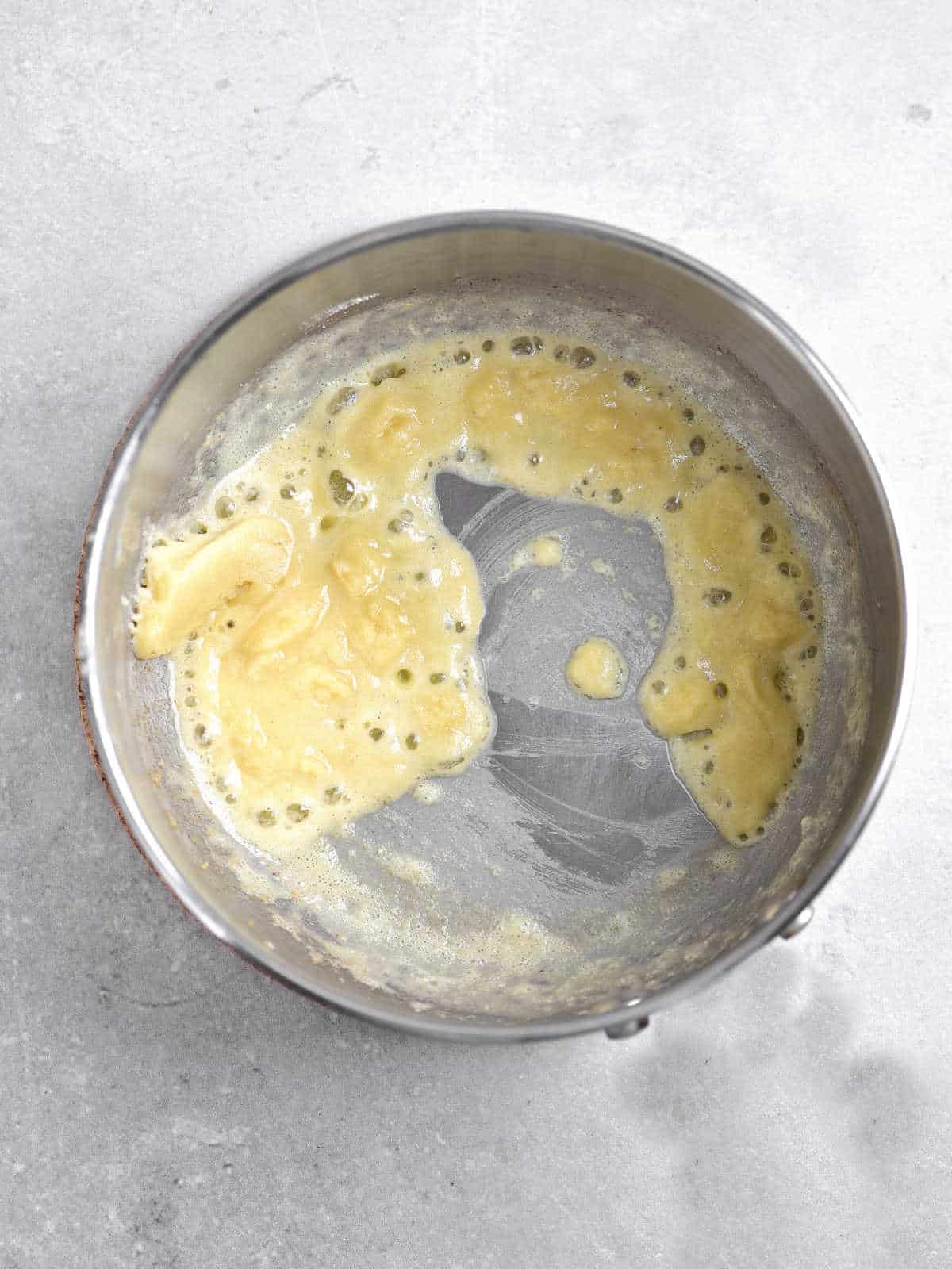 Mixture of butter and flour in a metal pan on a light grey surface.