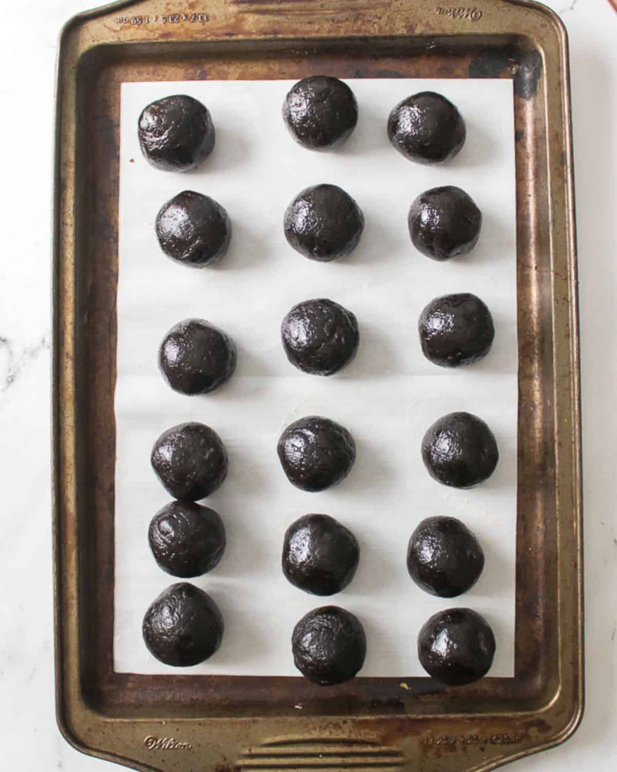 Metal tray with white parchment paper with oreo truffle balls.
