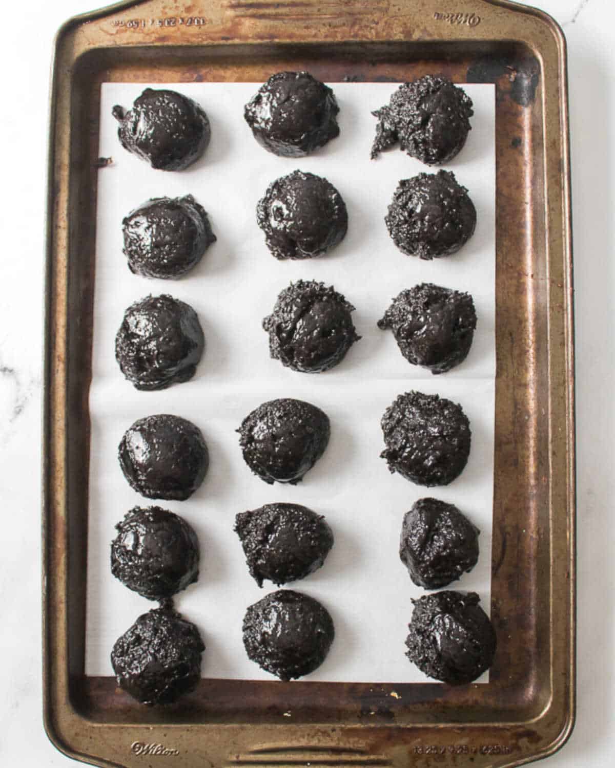 Parchment lined metal tray with mounds of oreo truffle mixture. Top view.