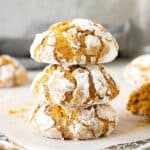 Close up o three pumpkin crinkle cookies in a stack on a white paper. Grey background.