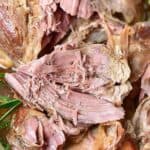 Brown and white text overlay on close up of roasted leg of lamb meat pieces.