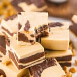 Close up of pile of chocolate peanut butter marbled fudge squares. Top one is bitten.