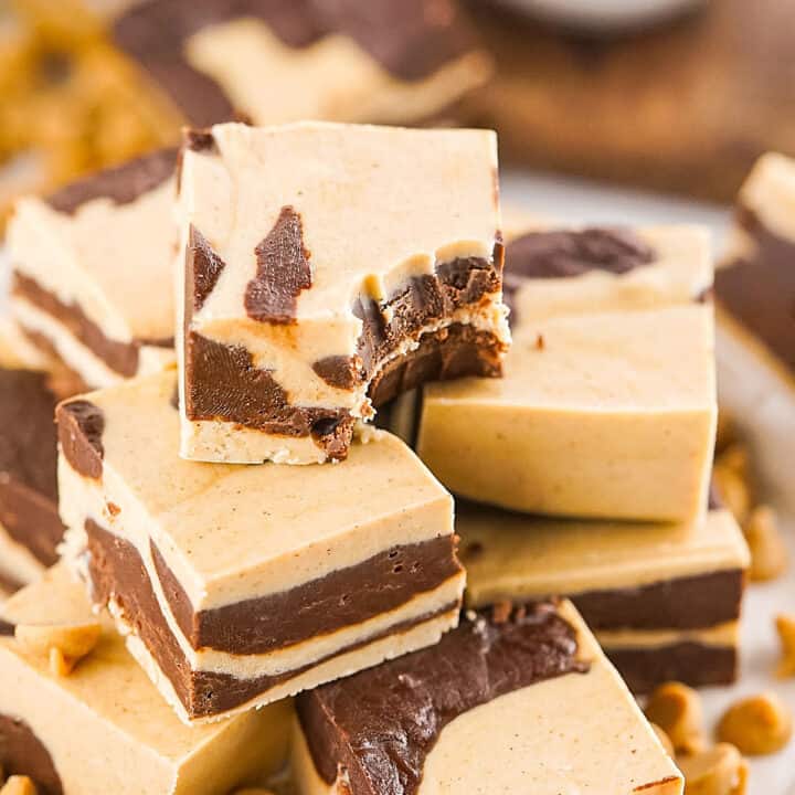 Close up of pile of chocolate peanut butter marbled fudge squares. Top one is bitten.