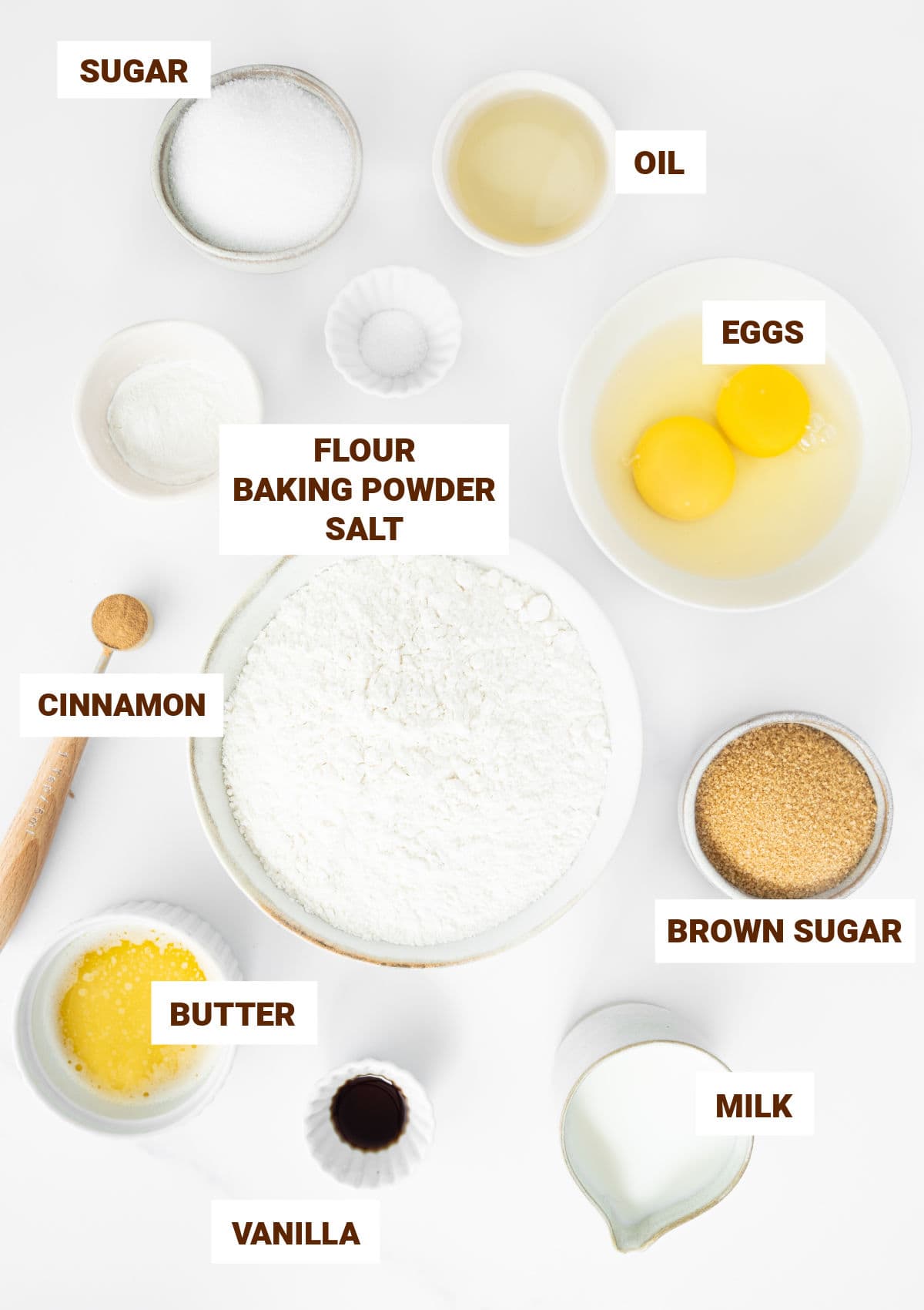 Ingredients for cinnamon crumb muffins in bowls on a white surface.