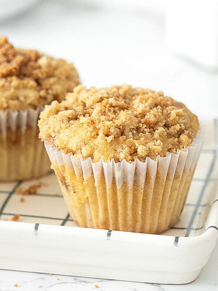 Close up cinnamon crumb muffins on a checkered white and blue dish. White background.