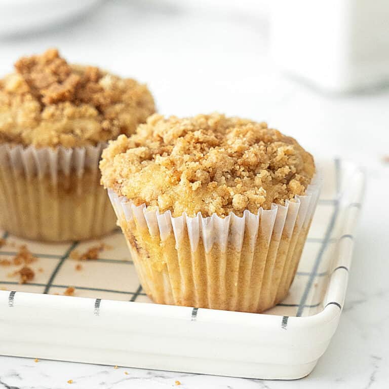 Close up cinnamon crumb muffins on a checkered white and blue dish. White background.