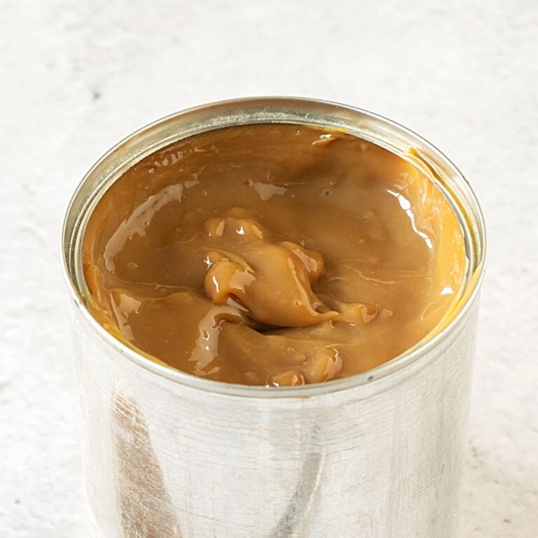 Close up of can of dulce de leche on a light gray surface.