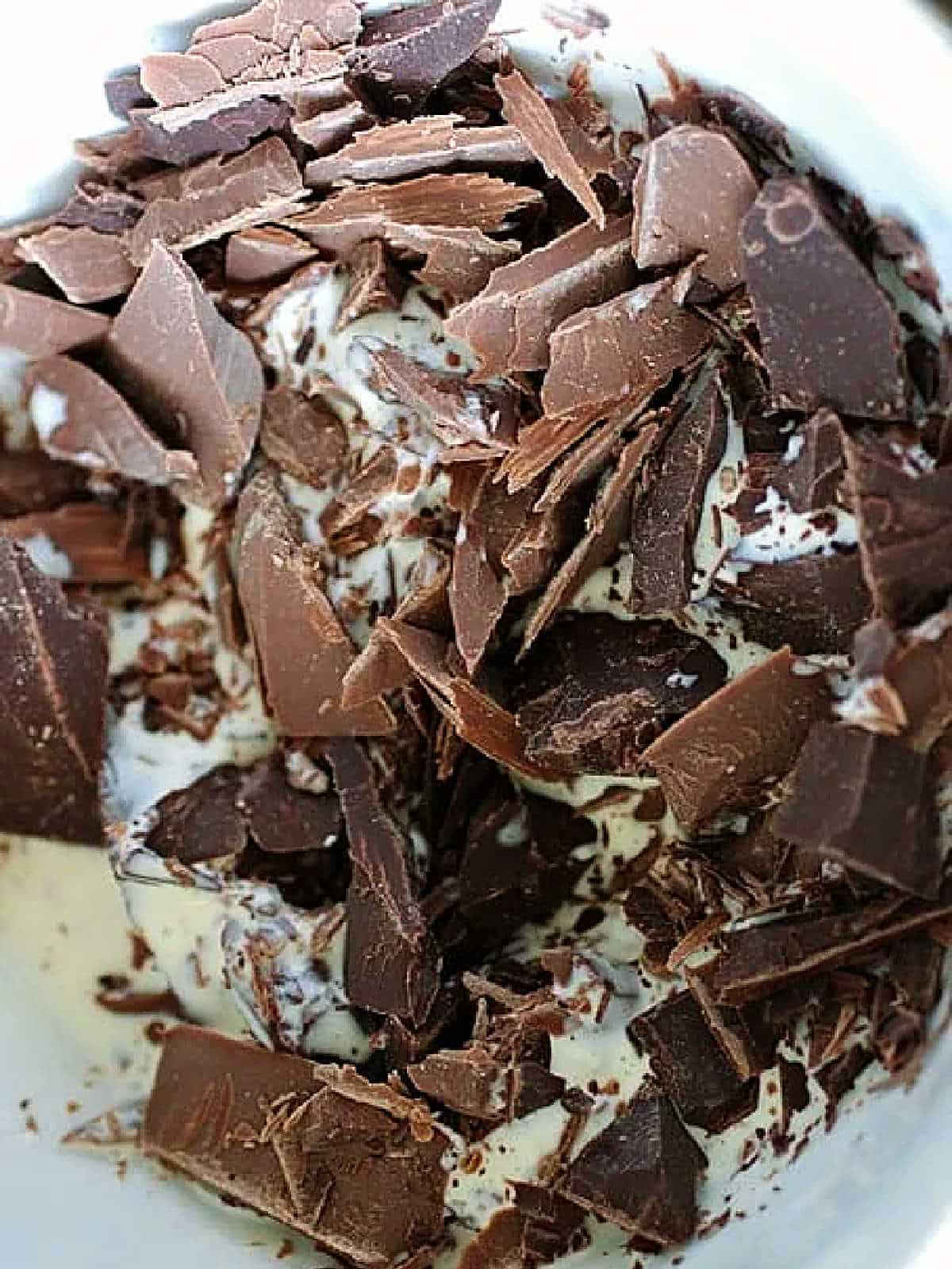 Close up of milk and dark chocolate pieces in a white bowl.