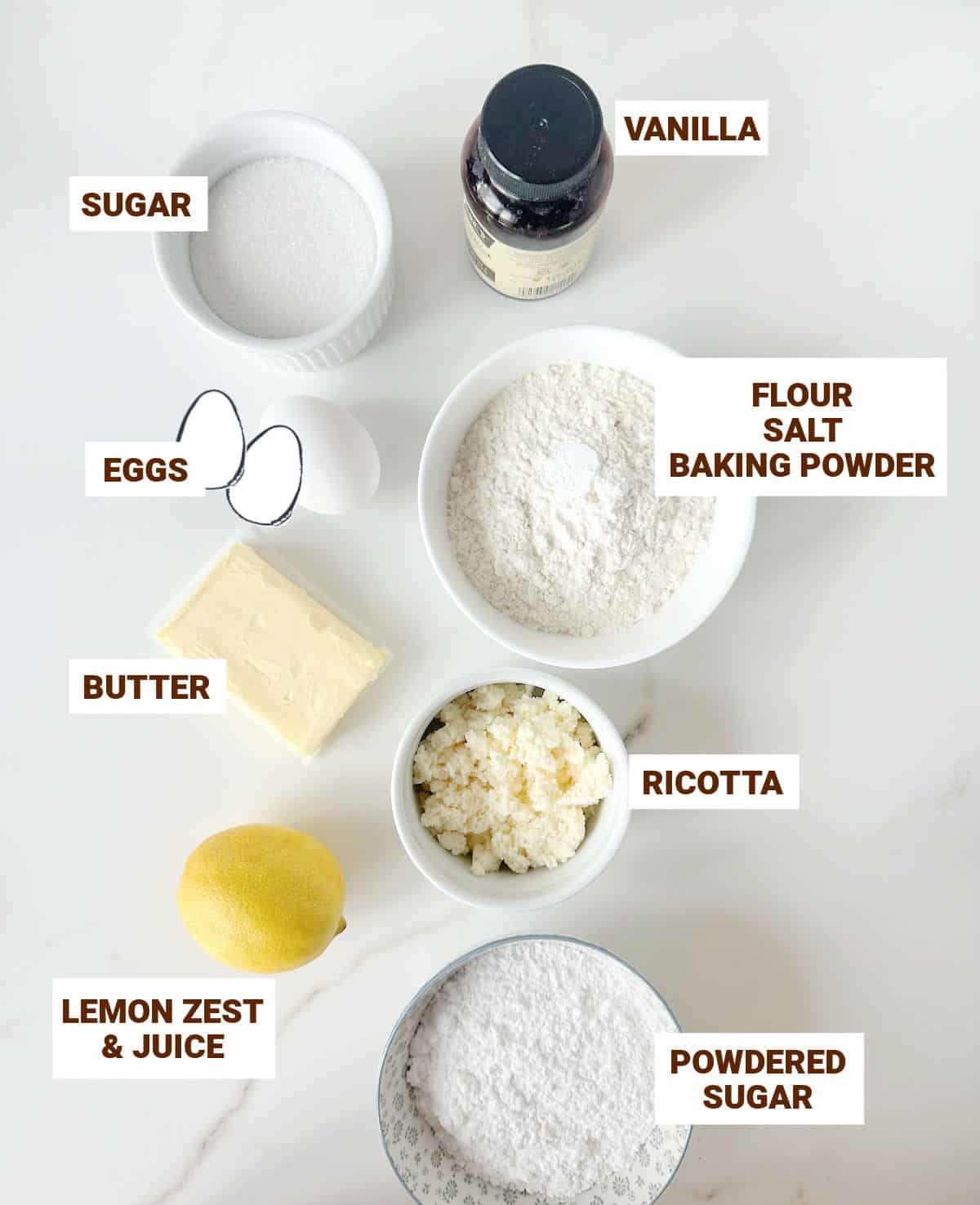 Ingredients for lemon ricotta cookies in bowls on a white marbled surface.